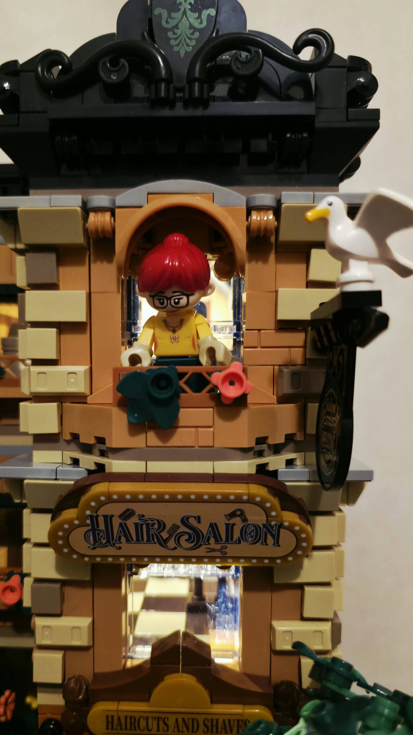 IAMBRICK Hair Salon mit rothaariger Figur am Balkon, weißer Möwe, Bogenfenstern und dekoriertem Ladenschild