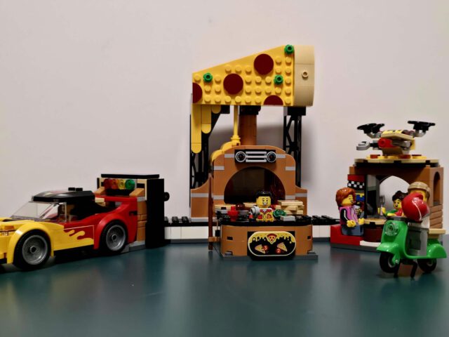 Gesamtansicht des LEGO City Sets 60496 mit Pizzaküche, Lieferauto und Sitzbereich