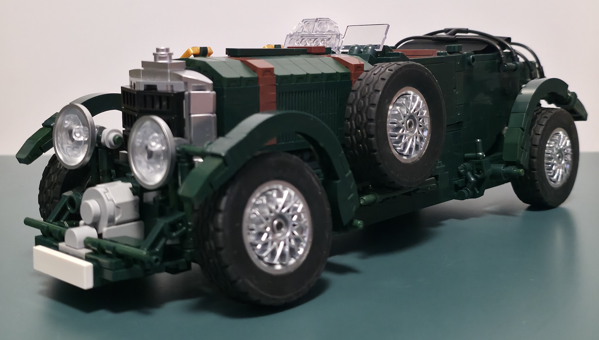 Mould King 10166 aus der seitlichen Dreiviertelperspektive mit Metallic-Speichenfelgen, seitlichem Ersatzrad und langer Motorhaube